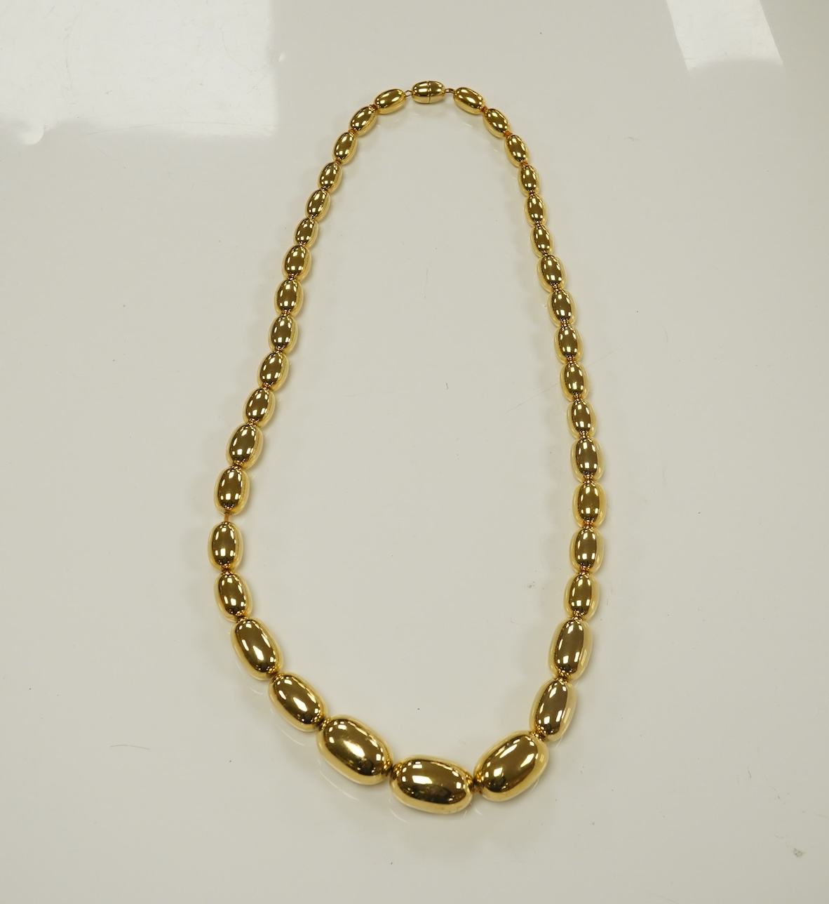 A modern gilt metal graduated oval bead costume necklace, 72cm. Condition - fair to good